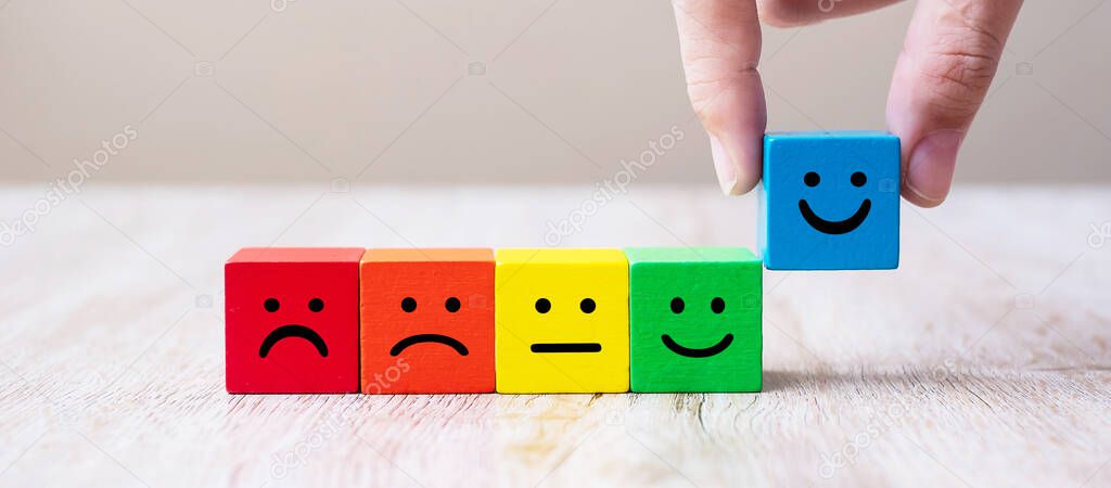 Emotion face symbol on yellow wooden cube blocks. Service rating, ranking, customer review, satisfaction and feedback concept.