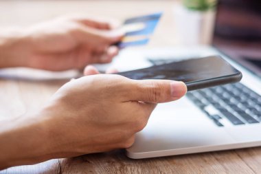 Adam evde sipariş verirken online alışveriş için akıllı telefon ve dizüstü bilgisayarla kredi kartını tutuyor. business, life style, technology, ecommerce, digital bankacılık ve online ödeme kavramı