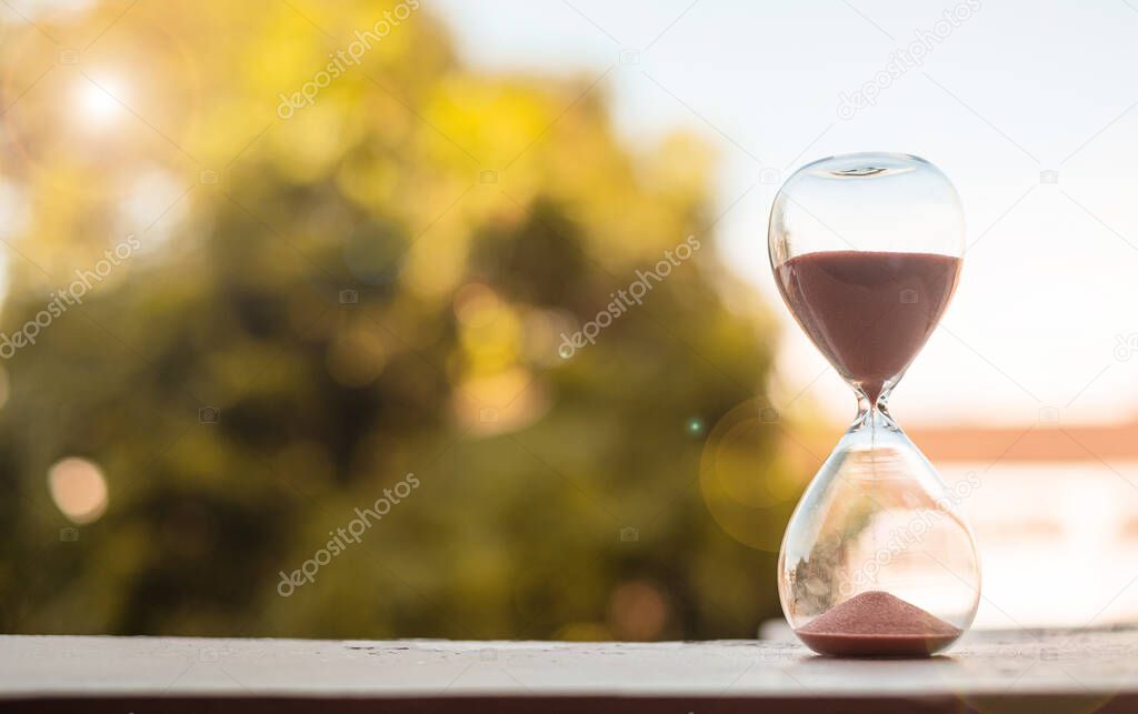 Hourglass on table, Sand flowing through the bulb of Sandglass measuring the passing time. countdown, deadline, Life time and Retirement concept