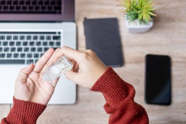 Evde çalışırken iş yerinde el temizleyicisi ve akıllı telefon cihazları ile el temizleyen kadın, Coronavirus (Covid-19) enfeksiyonu. Kişisel hijyen ve Yeni Normal kavramı