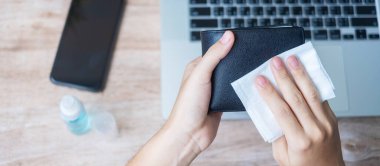 İş yerinde iş yerinde ıslak mendil ve alkol dezenfektanı ile para cüzdanını ve aletleri temizleyen kadın, koruma koronavirüsü (Covid-19) enfeksiyonu. Yeni Normal ve Temiz yüzey kavramı