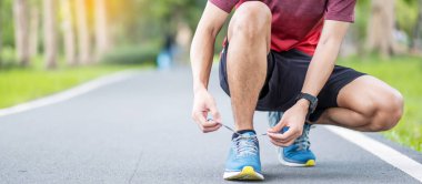 Spor giyim ve spor ayakkabı bağcıklarıyla parkta koşan genç bir erkek sporcu, sabahları koşuya ve koşuya hazır. Egzersiz, sağlık, sağlıklı yaşam tarzı ve egzersiz konsepti.