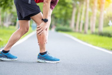 Koşu sırasında kas ağrısı çeken genç bir erkek. Baldır kasları çekildiği için bacak ağrısı çeken bir koşucu. Spor yaraları ve tıbbi konsept