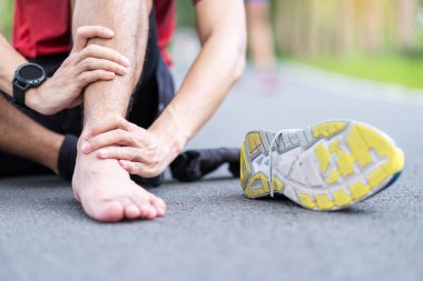 Koşu sırasında kas ağrısı çeken genç bir erkek. Ayak bileği burkulması ya da aşil tendoniti yüzünden bacağı ağrıyan bir koşucu. Spor yaraları ve tıbbi konsept