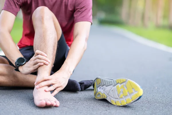 Young adult male with his muscle pain during running. runner man having leg ache due to Ankle Sprains or Achilles Tendonitis. Sports injuries and medical concept