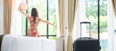 Modern otel odasında, mutlu, genç bir kadın pencereyi açıyor, Asyalı kadın turist güzel doğa manzarasına bakıyor. Seyahat, rahatlama, yolculuk, gezi ve tatil kavramları zamanı