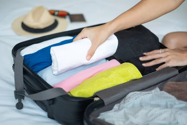 Young adult female packing luggage for summer vacation. woman tourist checking list travel accessories in suitcase on the bed. Time to travel, relaxation, journey, trip and weekend concepts