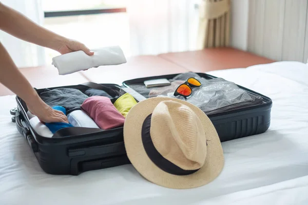 Young adult female packing luggage for summer vacation. woman tourist checking list travel accessories in suitcase on the bed. Time to travel, relaxation, journey, trip and weekend concepts