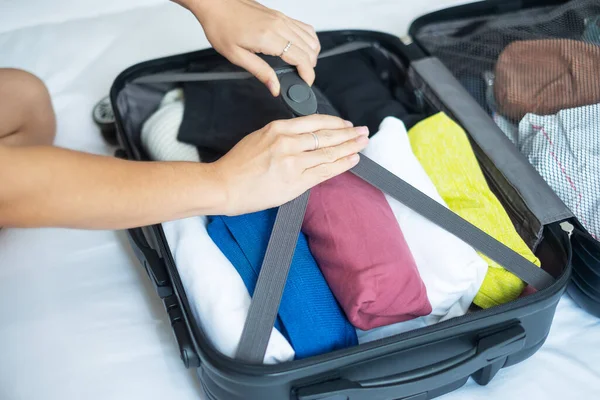 Young adult female packing luggage for summer vacation. woman tourist checking list travel accessories in suitcase on the bed. Time to travel, relaxation, journey, trip and weekend concepts