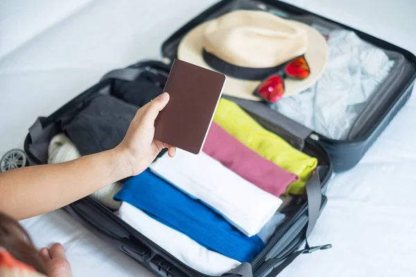 Young adult female packing luggage for summer vacation. woman tourist checking list travel accessories in suitcase on the bed. Time to travel, relaxation, journey, trip and weekend concepts