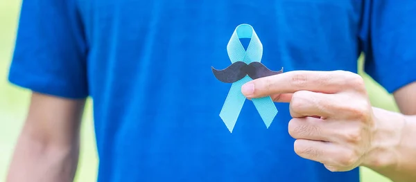 November Prostate Cancer Awareness month, adult Man holding Blue Ribbon with mustache for supporting people living and illness. Healthcare, International men, Father and World cancer day concept