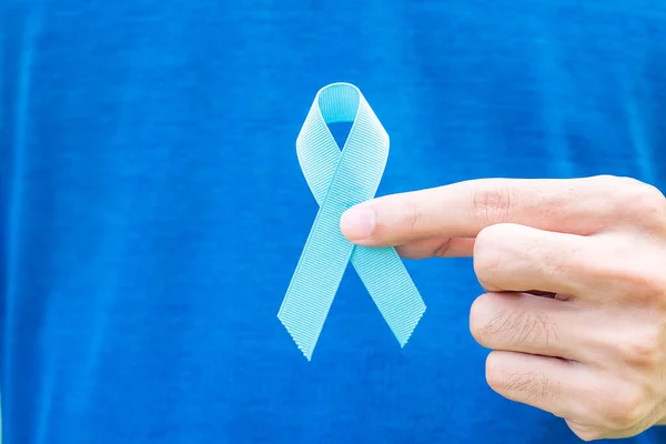 November Prostate Cancer Awareness month, Man in blue T shirt with hand holding Blue Ribbon for supporting people living and illness. Healthcare, International men, Father and World cancer day concept