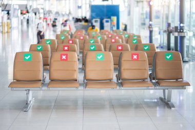 Uluslararası havaalanındaki koltukta sembol çıkartması. Yeni Normal ve Sosyal Mesafe Kavramları, Koronavirüs Hastalığı (Covid-19) enfeksiyonu