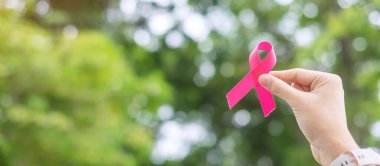 Ekim Kanser Farkındalığı Ayı, Pembe Kurdele 'yi elinde tutan yetişkin kadın, yaşayan ve hastalıkları desteklemek için yeşil bir geçmişi var. Uluslararası Kadınlar, Anne ve Dünya Kanser Günü Konsepti