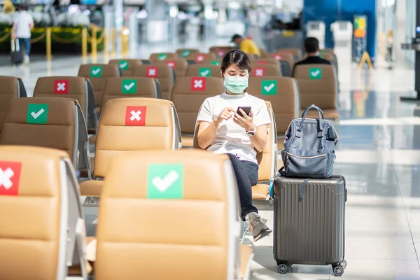 마스크를 착용하고 공항에서 스마트폰을 사용하는 의자에 아시아 코로나 바이러스 Covid — 스톡 사진
