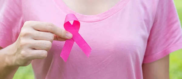 October Breast Cancer Awareness month, adult Woman in pink T- shirt with hand holding Pink Ribbon for supporting people living and illness. International Women, Mother and World cancer day concept