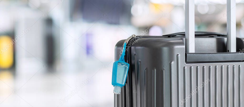 Luggage bag with alcohol gel hand sanitizer in international airport terminal, protection Coronavirus disease (Covid-19) infection. New Normal and travel bubble concepts