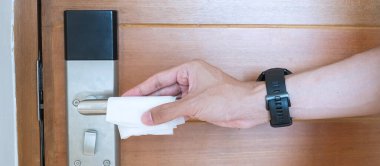 İnsan eliyle dijital kapı kulpu ıslak mendil, koronavirüs ya da Corona Virüs Hastalığı (Covid-19) ile kamu odasında temizlenir. Temiz yüzey, yaşam tarzı, güvenlik seyahati ve yeni normal kavram