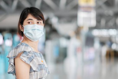 Havaalanı terminalinde yüz maskesi takan genç bir kadın, Coronavirus hastalığı enfeksiyonunu koruyan, seyahat etmeye hazır Asyalı bir kadın yolcu. Yeni Normal ve COVID-19 konsepti altında seyahat