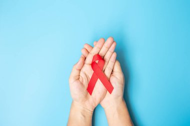 Red Ribbon 'ı yaşayan ve hastalıkları desteklemek için tutan adam. Sağlık ve güvenli seks konsepti. Aralık Dünya Yardım Günü Farkındalık Ayı