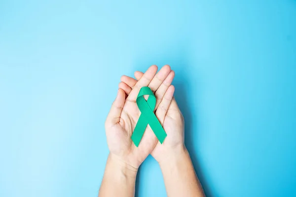 September Ovarian cancer Awareness month, Woman holding teal Ribbon color on blue background for supporting people living, and illness. Healthcare and world cancer day concepts
