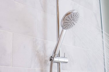 Su damlaları duş başlığı ve musluktan akıyor ve modern banyoda mermer duvar arkaplanı var.