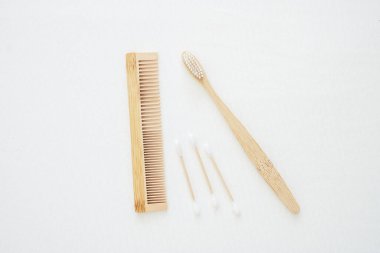 Bambu diş fırçası, pamuk tomurcuk ve beyaz yatak arka planında tarak. Çevre Koruma, Sıfır Atık, Yeniden Kullanılabilir, Plastiksiz, Dünya Çevre Günü ve Dünya Günü kavramı