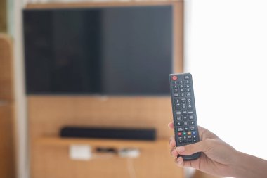 Ev veya lüks oteldeki modern odadaki Smart TV 'yi ayarlamak için uzaktan kumanda kullanılıyor.