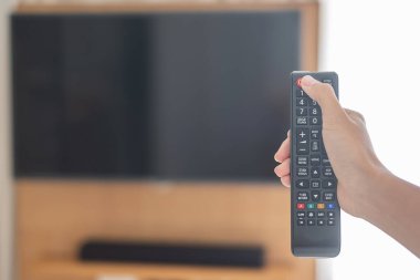 Ev veya lüks oteldeki modern odadaki Smart TV 'yi ayarlamak için uzaktan kumanda kullanılıyor.