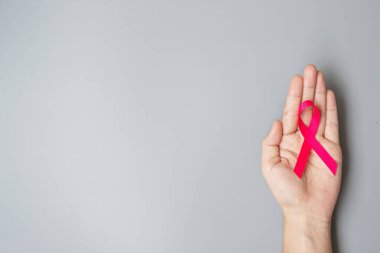 Ekim Kanser Farkındalığı Ayı, Pembe Kurdele 'yi elinde tutan yetişkin kadın, yaşayan ve hastalıkları desteklemek için gri arka planda. Uluslararası Kadınlar, Anne ve Dünya Kanser Günü Konsepti