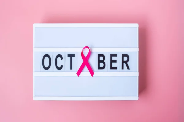 Breast Cancer Awareness month, Pink Ribbon on lightbox with OCTOBER text background for supporting people living and illness. International Women, Mother and World cancer day concept