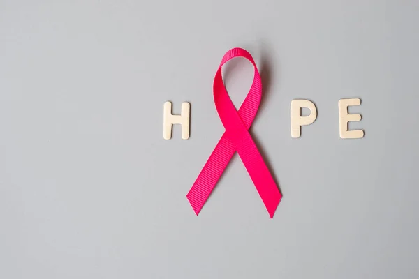 October Breast Cancer Awareness month, Pink Ribbon with HOPE text on grey background for supporting people living and illness. International Women, Mother and World cancer day concept