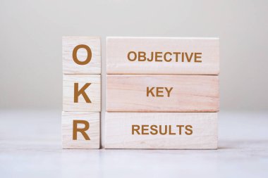 Masa arkaplanındaki OKR metni (Hedefler, Anahtar ve Sonuçlar) tahta küp blokları. iş hedefi ve odaklanma kavramları