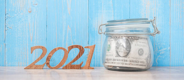 2021 New Year with money glass jar and wooden number. financial, Resolution, Goals, Plan and saving Concept