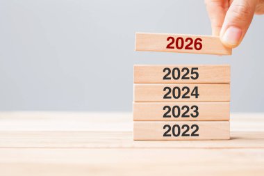 2025 üzerinde 2026 blok ve masa arkasında 2024 ahşap bina. İş planlaması, Risk Yönetimi, Çözüm, Strateji, Çözüm, Hedef, Yeni Yıl Yeni Sen ve Mutlu Noeller kavramları