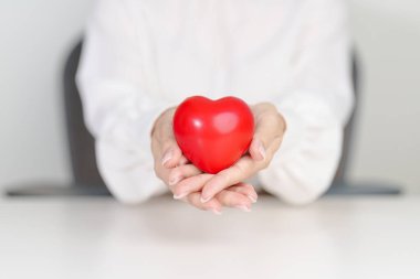 Kadın eli kırmızı kalp şeklinde. Aşk, donör, Eylül ayı kalp günü, dünya sağlık günü, CSR bağışı ve sigorta kavramları