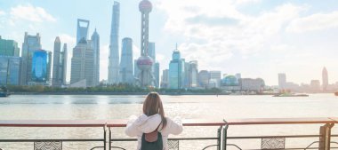 Çin, Şangay 'ı ziyaret eden bir kadın gezgin. Sırt çantalı bayan turist Şangay 'ın kuzeyindeki Lujiazui' nin Şangay manzarasına bakıyor. tarihi eser ve turizm turizmi için popüler.