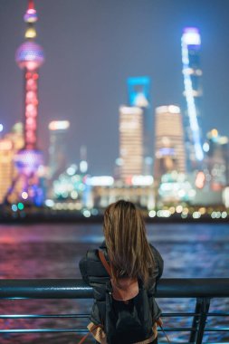 Çin, Şangay 'ı ziyaret eden bir kadın gezgin. Sırt çantalı bir bayan turist Şangay 'da Lujiazui' nin Şangay 'daki Bund of Shanghai manzarasını seyrediyor. tarihi eser ve turizm turizmi için popüler.