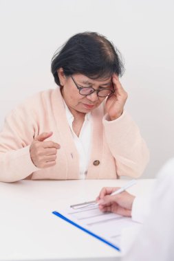 Kıdemli kadın baş ağrısı çekiyor ve bir hastalığa danışmanlık yapıyor. Yaşlı sağlık hastası, Tıbbi Teşhis, Migren, Beyin Tümörü, Beyin Felci, Bunama, Nörolojik Bozukluk, Alzheimer, Parkinson