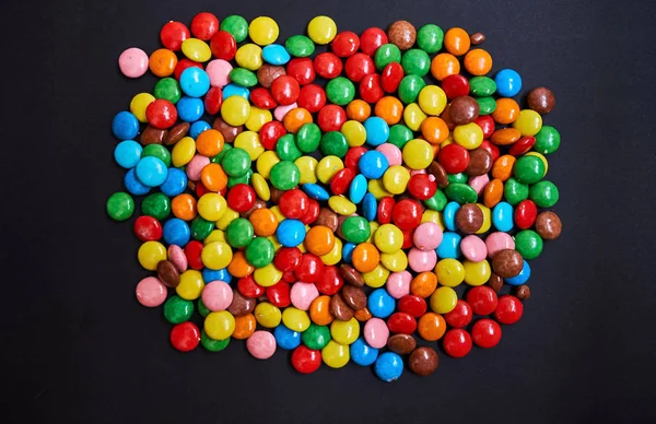 Color small chocolate dragee. Candy on a black background. — Stock Photo, Image