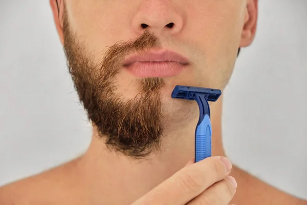 Jovem Usando Uma Navalha Azul Descartável Rapa Sua Cerda Isolada — Fotografia de Stock