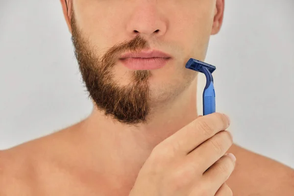 Jovem Usando Uma Navalha Azul Descartável Rapa Sua Cerda Isolada — Fotografia de Stock