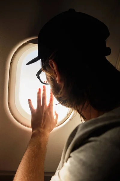Молодой человек смотрит в окно самолета — стоковое фото