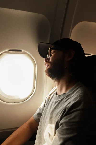 Молодой человек спит у окна самолета — стоковое фото