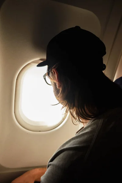 Молодой человек смотрит в окно самолета — стоковое фото