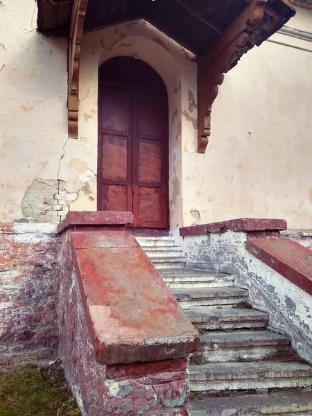 La façade d'une vieille maison abandonnée avec une porte et des marches — Photo