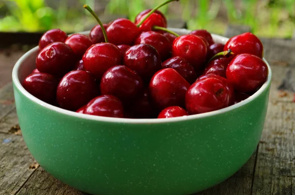 Red ripe cherries in a green plate in the garden — Stock Photo, Image