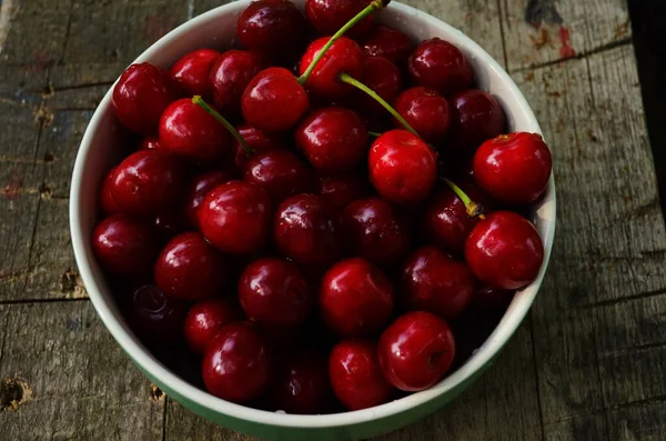 Bahçedeki yeşil bir tabakta kırmızı kirazlar — Stok fotoğraf