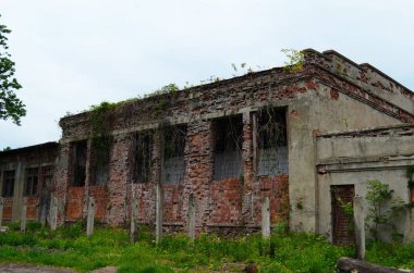 Pencereleri kırık, terk edilmiş eski bir tuğla binanın duvarı..