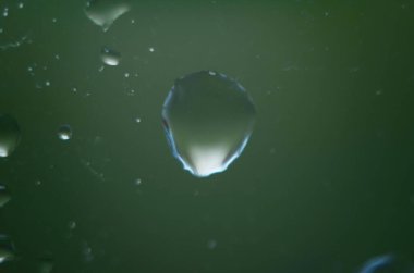 Bulutlu arka planda cam yüzeyine yağmur damlaları düşer. Bulutlu arkaplanda izole edilmiş doğal yağmur damlaları deseni.